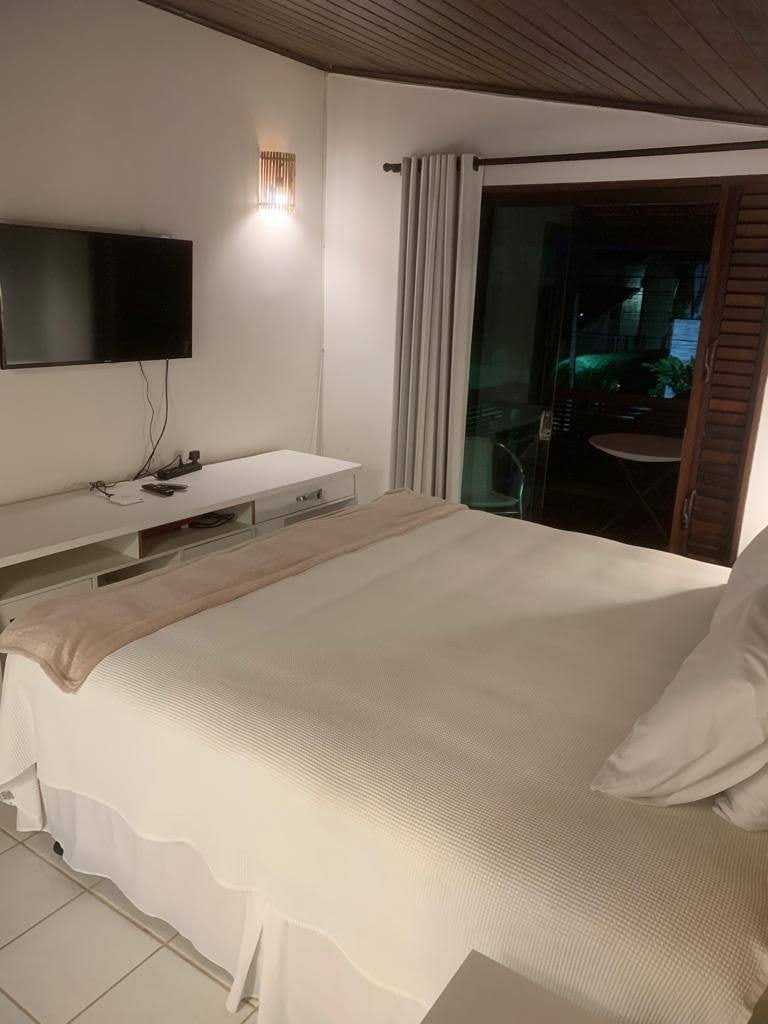 Suíte com cama, TV e porta para a varanda
